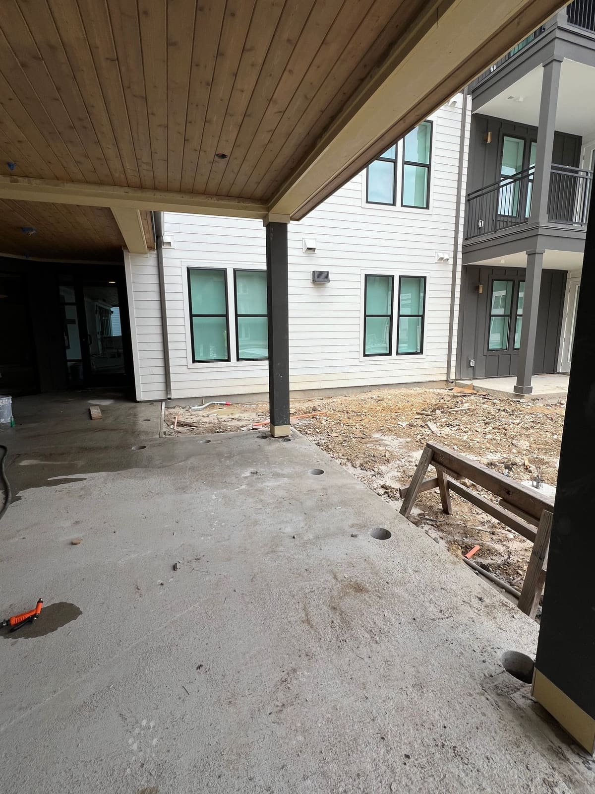 Core-drilled holes in a concrete patio slab under a covered porch