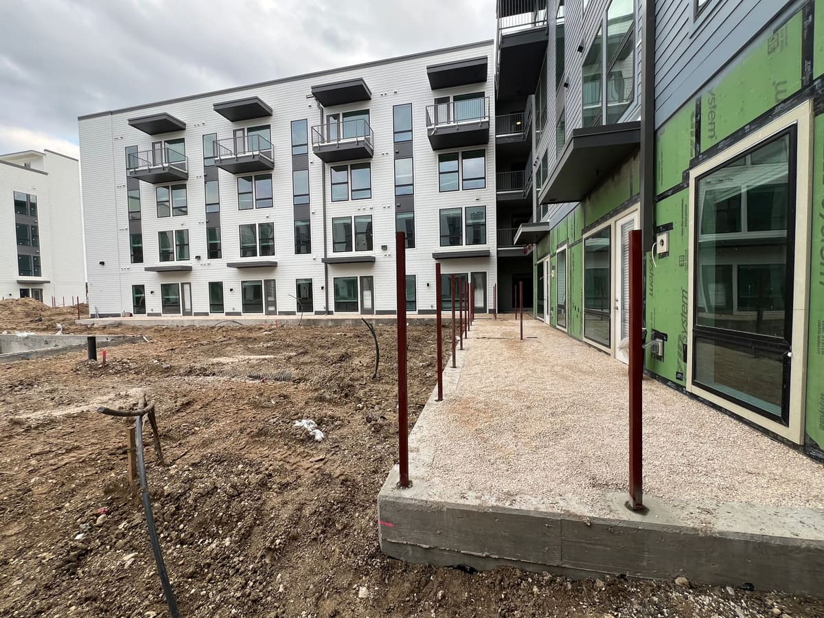 Steel fence posts core drilled into a concrete curb along an apartment courtyard