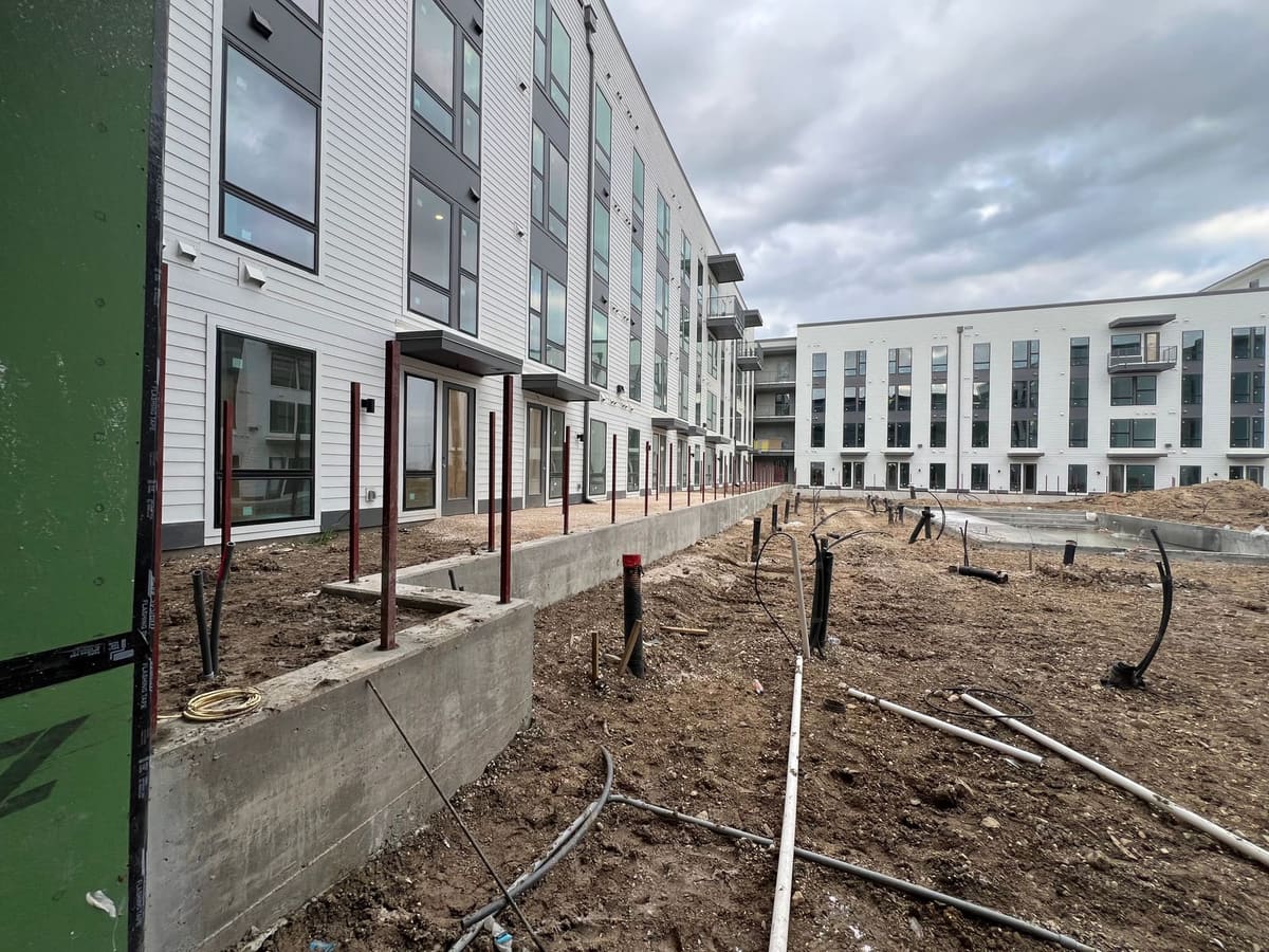 Row of fence posts set into a concrete walkway curb on a commercial site