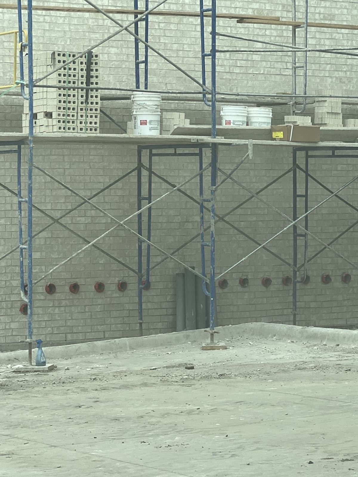 Rows of drilled penetrations with conduit sleeves through a concrete wall