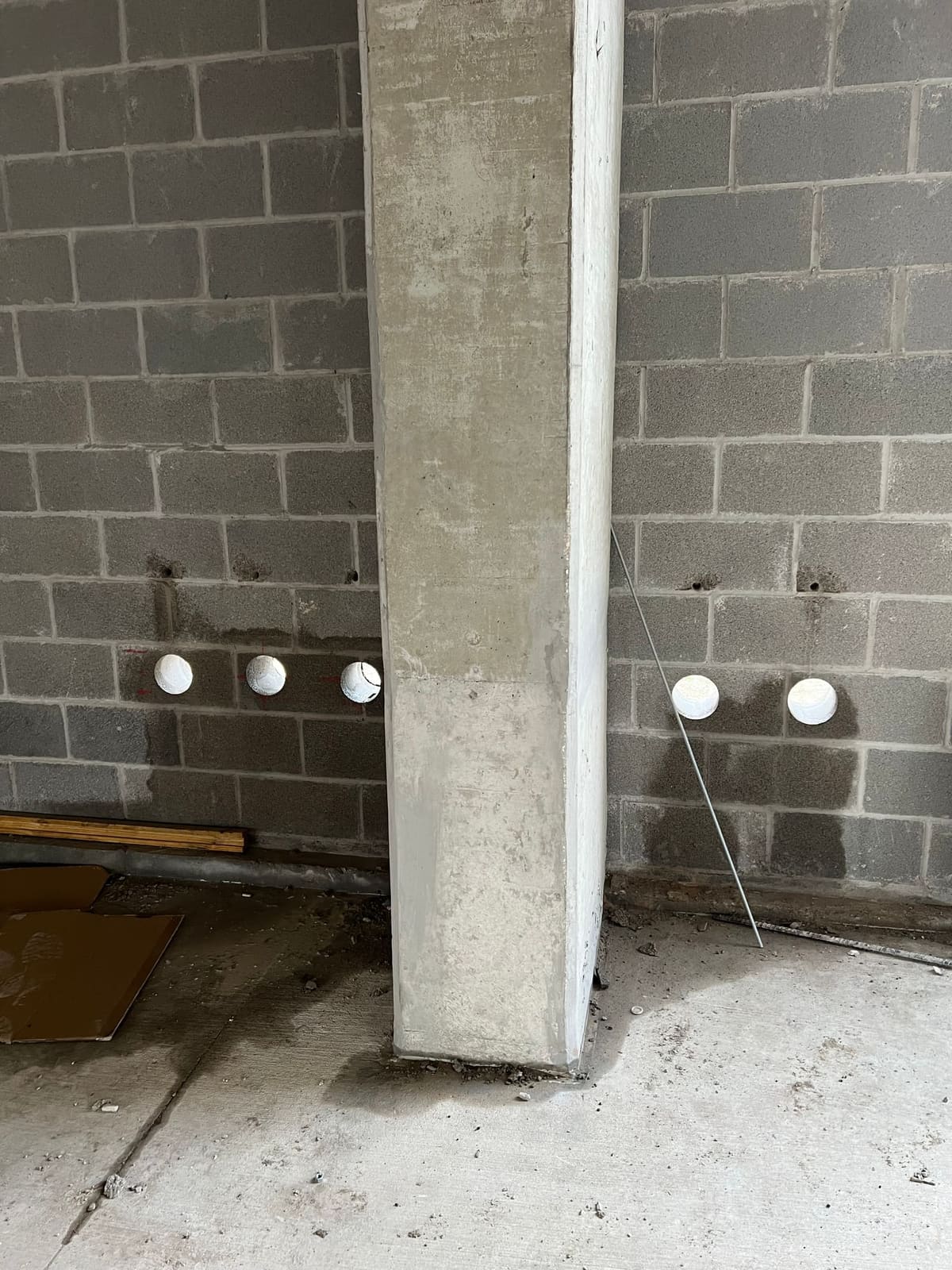 CMU wall with a row of capped penetrations behind scaffolding