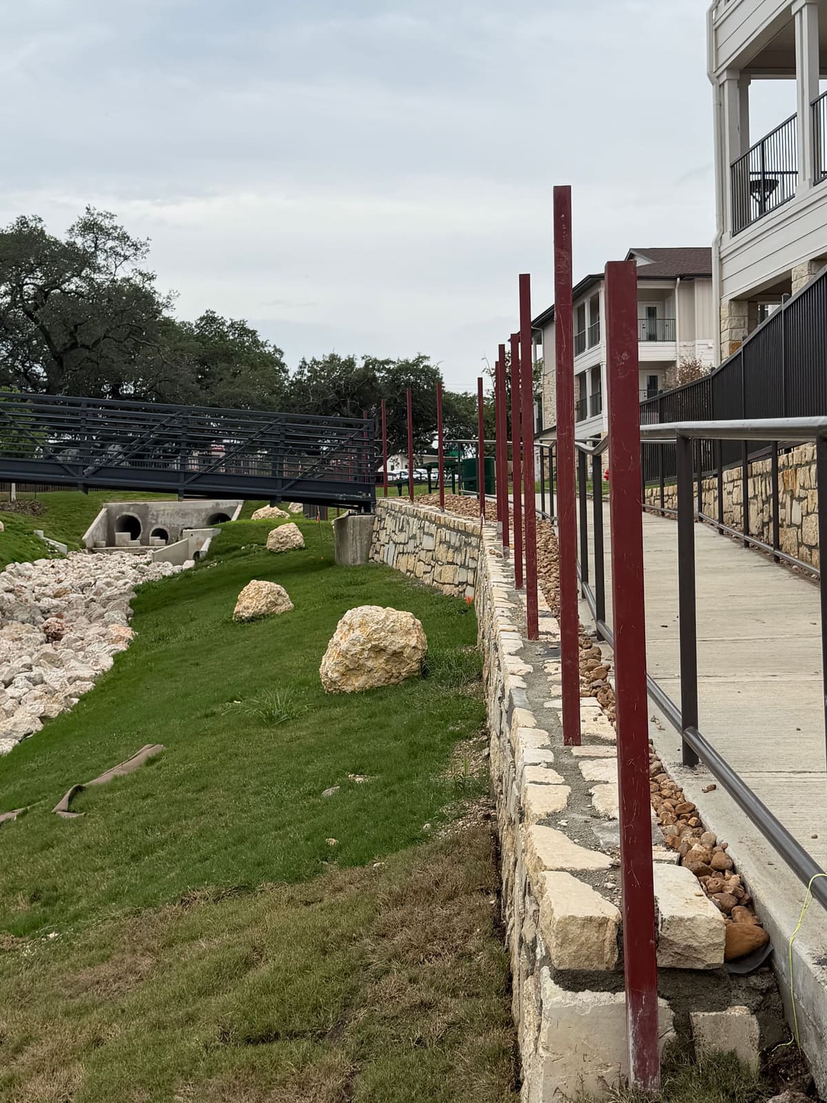 Fence posts core drilled into a stone retaining wall cap along a courtyard