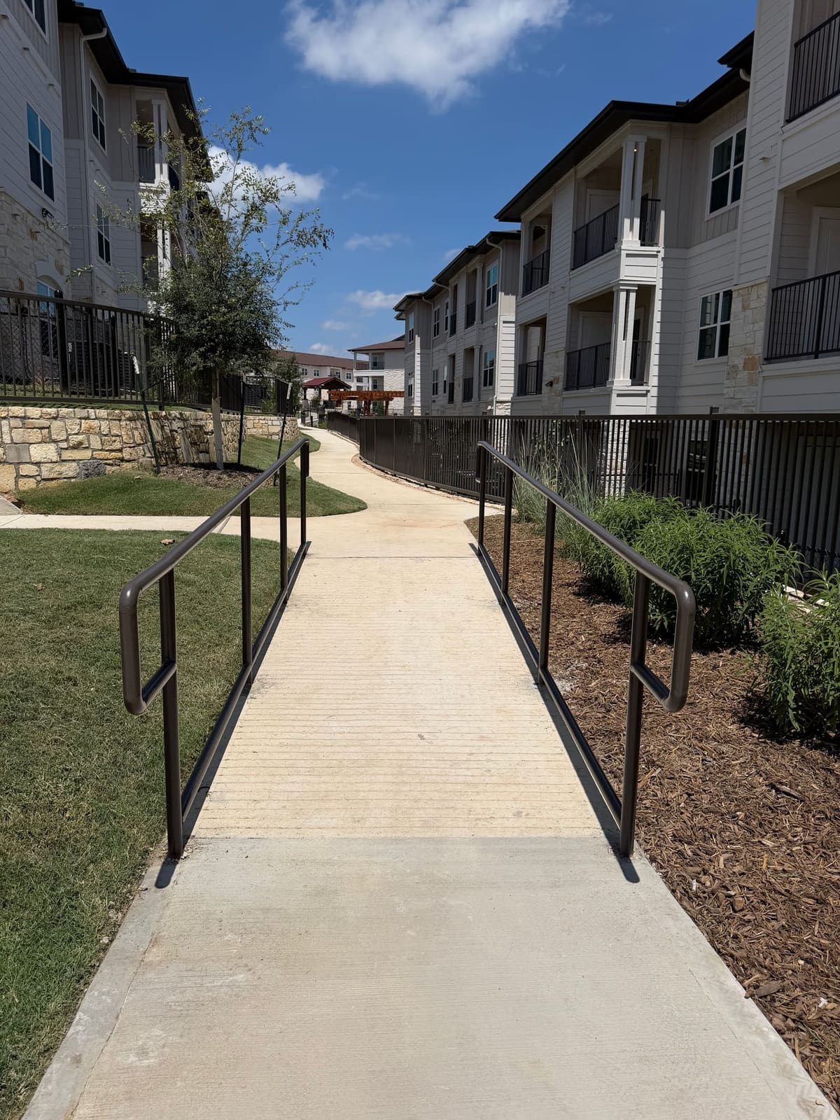 ADA ramp with metal handrails anchored into a concrete walkway