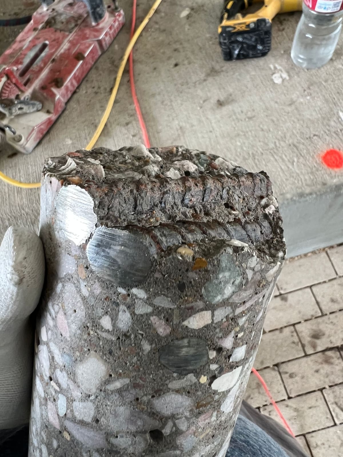 Close-up cross-section of drilled holes through a concrete edge, showing rebar and aggregate